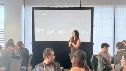 Nicole on stage in front of The 5 Tables slide