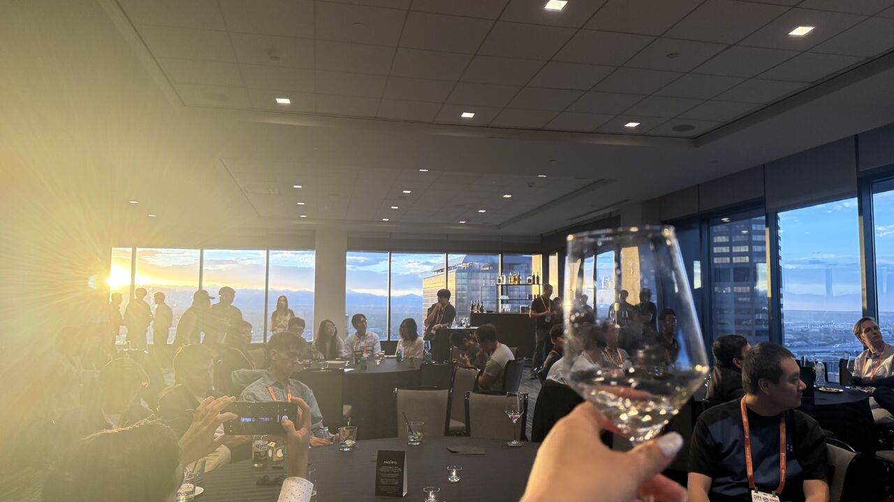 A raised glass and dinner tables in Denver's golden sunset light